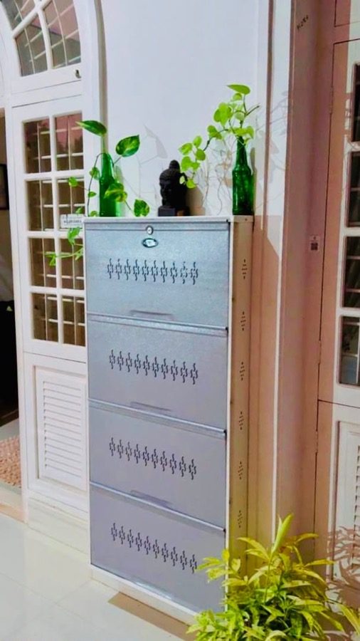 Grey White four-tier steel shoe rack beside louvred doors with plants and ornaments on top